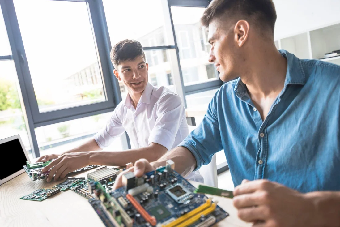 Two technicians repairing a computer motherboard